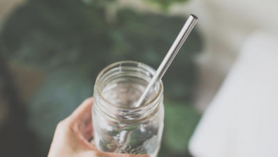 Hand holding mason jar with metal straw